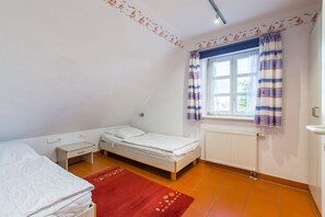 A small, single-room apartment with a bed, a desk, a radiator, and a window with curtains. - Beachfront vacation apartment with private terrace - Feriendorf Bakenberg FeWo B66 - (Dranske)