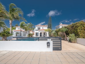 A residential area with a swimming pool, white buildings, and palm trees. - Ayia Napa Holiday Villa Sv11 (Sotira)