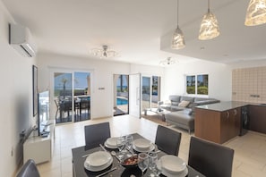 A modern kitchen with a dining area, a sofa, and a view of the outdoors. - Ayia Napa Holiday Villa Sv11 (Sotira)