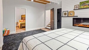 Ein Schlafzimmer mit Bett, Kamin, einer Tür zu einem anderen Raum und einer Treppe.