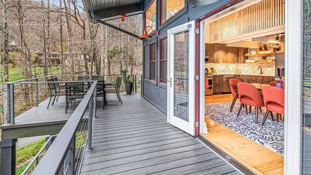 Ein modernes Haus mit Terrasse, Essbereich und sichtbarer Küche durch Glastüren.
