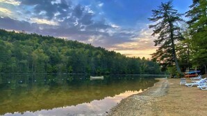 A lake with a dock, surrounded by dense forest and a clear sky. - Riverfront Cabin | Sauna • Hot Tub • Private Trail (Cashiers)