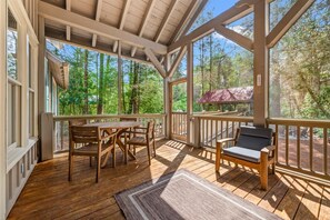 Eine Holzterrasse mit Tisch und Stühlen, einer gepolsterten Bank und einem mit Metall gedeckten Pergola.