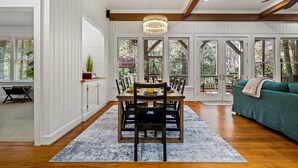 A dining area with a wooden table, chairs, and a chandelier. - Riverfront Cabin | Sauna • Hot Tub • Private Trail (Cashiers)