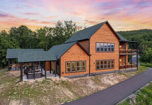 A two-story wooden cabin with a covered patio and a second-story balcony. - Amazing Mountain Views | Indoor Pool | Game Room (Sevierville)