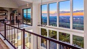 Un edificio de gran altura con amplias ventanas que ofrecen vistas a la ciudad, un balcón con barandilla y un diseño interior moderno.