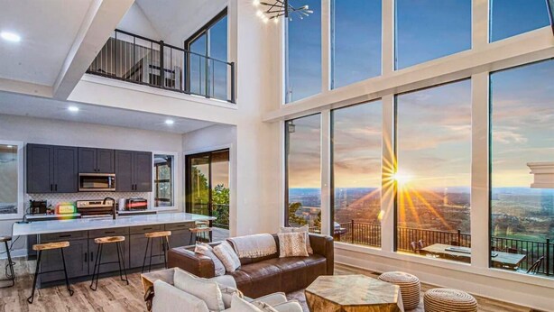 Un interior moderno con cocina, comedor y ventanas amplias que ofrecen vistas a la ciudad.