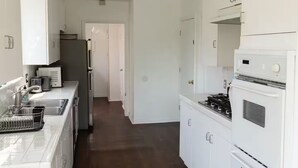 Et moderne køkken med hvide skabe, en stålvask og en gasblus.