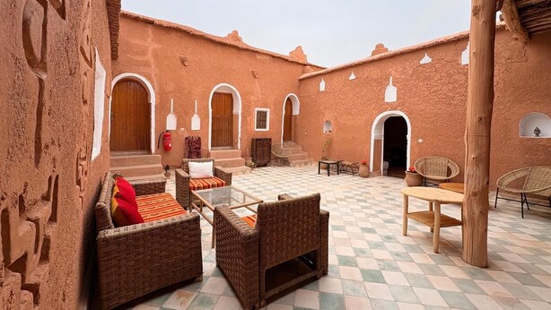 A courtyard with wicker furniture, a checkered floor, and rustic architecture. - Tigmi Hamid (Assfalou)