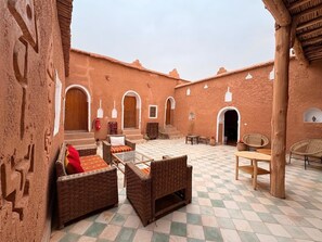 A courtyard with wicker furniture, a checkered floor, and rustic architecture.