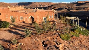A traditional adobe building with a flat roof, a central doorway, and a small porch area. - Tigmi Hamid (Assfalou)