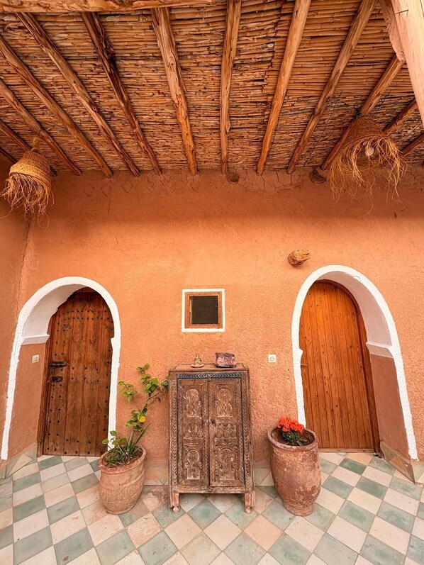 A traditional building with a thatched roof, two wooden doors, and a central cabinet with decorative carvings.