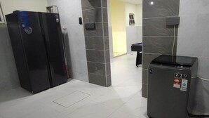 Een hotellobby met een receptiebalie, een prullenbak en een intercomsysteem aan de muur.