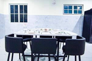 A dining area with a round table, four chairs, and a window with blinds.