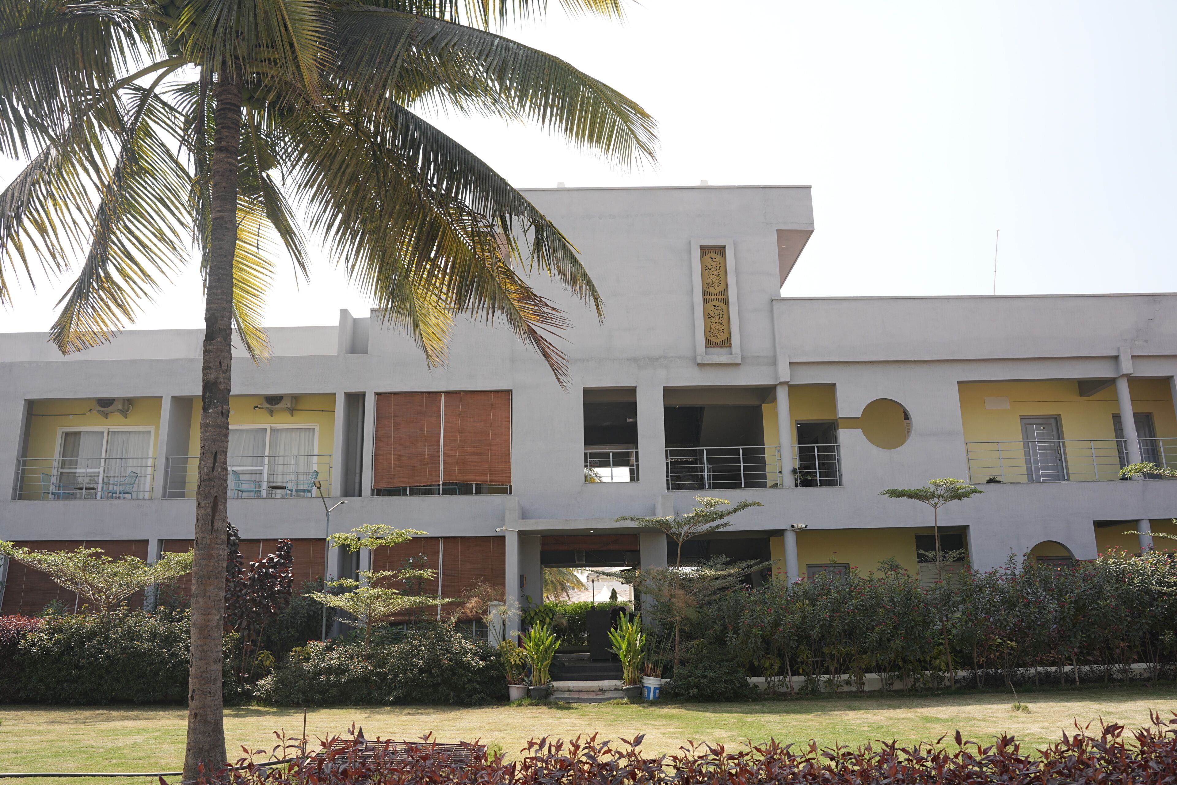 A multi-story building with a flat roof, large windows, and a central courtyard with a palm tree.