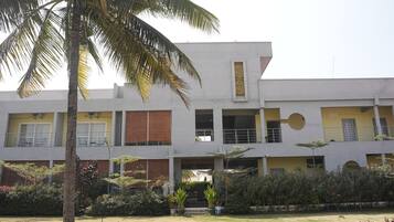 A multi-story building with a flat roof, large windows, and a central courtyard with a palm tree.