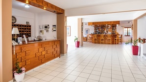 A hotel lobby with a reception desk, a bar area, and a tiled floor. - Casa Garden (Karpathos)