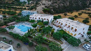 An aerial view of a hotel with a swimming pool, multiple buildings, and surrounding greenery. - Casa Garden (Karpathos)
