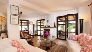 A spacious living room with a fireplace, a dining area, and a view of the outdoors. - Villa Jacobus (Pollença)