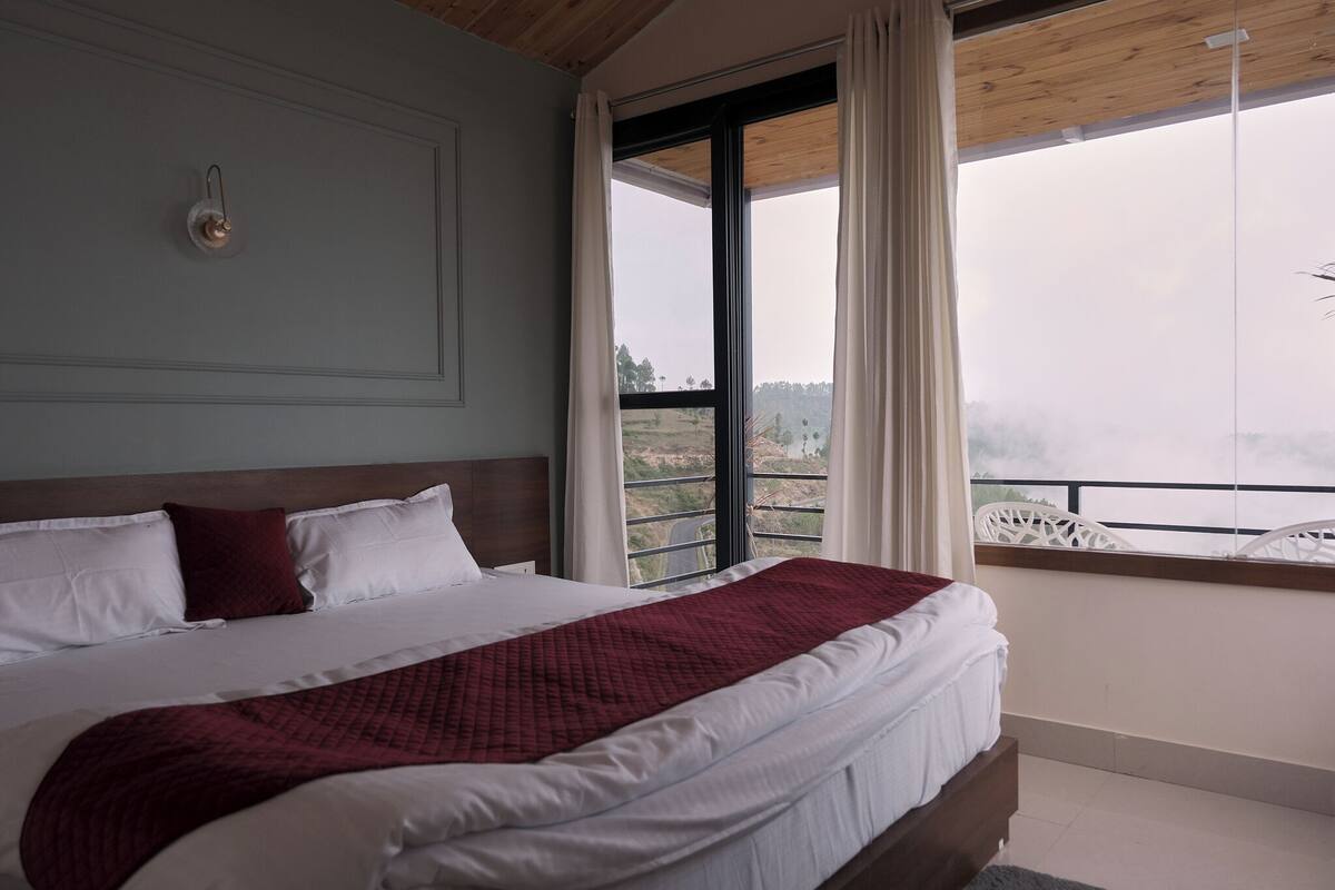 Une chambre avec un grand lit, une fenêtre avec des rideaux et une vue sur l’extérieur.