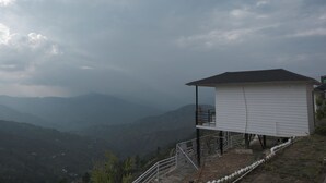 Ein weißes Gebäude mit Balkon, gelegen an einem Hang mit Blick auf ferne Berge.