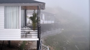 Ein weißes Gebäude mit Balkon, Pflanze und Stuhl.
