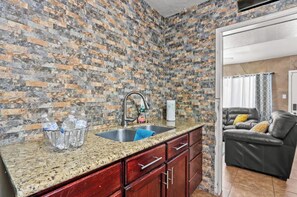 A kitchen with a granite countertop, a stainless steel sink, and a brick-patterned backsplash. - Peaceful 3BR/1BA Home near DT and Hiking Serene (El Paso)