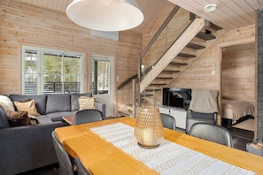 A wooden interior with a sofa, dining table, and staircase.