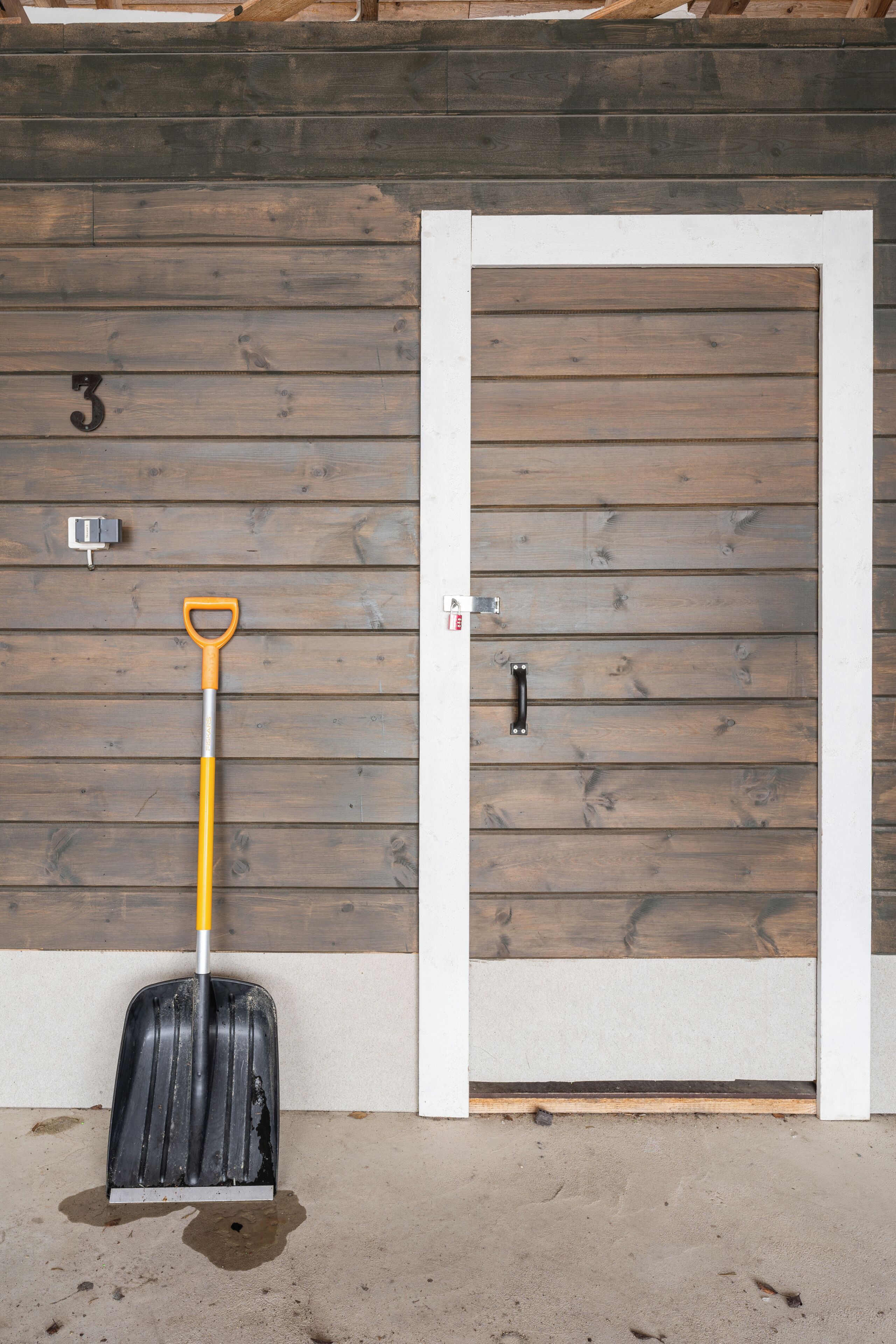 A room with a wooden wall, a door with a handle, and a number '3' on the wall.