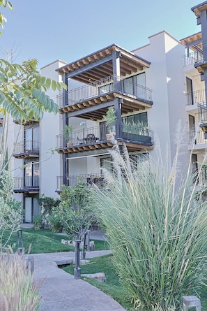 A multi-story residential building with balconies, a paved pathway, and surrounding greenery. - Private Hot Tub - 5BR in Nueva Escondida (San Miguel de Allende)