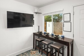 Eine Küche mit Flachbildfernseher an der Wand, einem Fenster mit Ausblick und einer Bar mit Hockern.