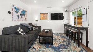 A modern living space with a sofa, coffee table, TV, and a dining area with chairs. - Desert Rose Retreat in the Heart of Downtown PHX (Phoenix)