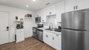A modern kitchen with white cabinets, stainless steel appliances, and wooden flooring. - Desert Rose Retreat in the Heart of Downtown PHX (Phoenix)