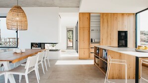 Une cuisine moderne avec un îlot central en bois, des chaises blanches et un luminaire suspendu.