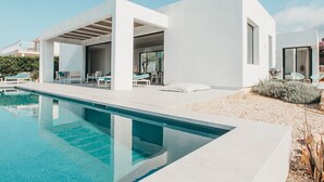Une maison moderne dotée d’une piscine, d’un espace salon extérieur et d’un jardin.