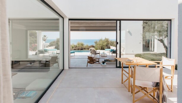 Un intérieur moderne avec une porte vitrée donnant sur un espace extérieur aménagé avec une piscine et une vue sur l’océan.