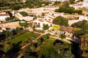 An aerial view of a historic town with stone buildings, a central courtyard, and surrounding greenery. - Villa Alaior with private pool - My Rental Homes (Alaior)