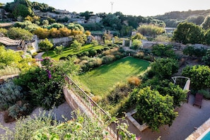 A landscaped garden with a central lawn, stone pathways, and surrounding vegetation. - Villa Alaior with private pool - My Rental Homes (Alaior)