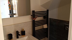 A bathroom with a white sink, black towel rack, and a toilet. - Charming studio in the heart of the mountains (Burzet)