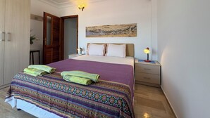 A bedroom with a bed, two bedside tables, a nightstand, a wardrobe, and a painting on the wall. - Duplex House on the Castle Road with a Sea view (Alanya)