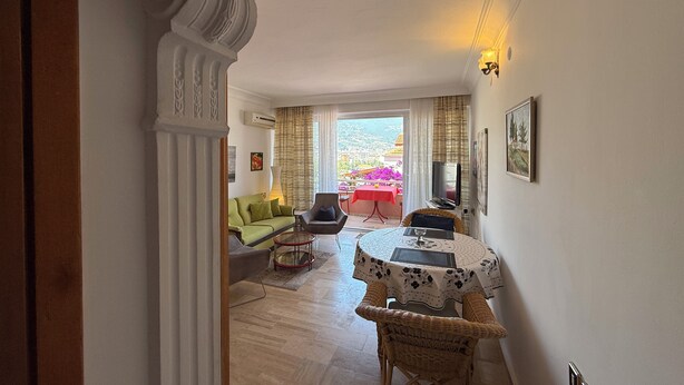A living room with a sofa, armchair, and a dining table with a basket. - Duplex House on the Castle Road with a Sea view (Alanya)