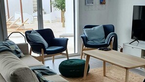 Un soggiorno moderno con un divano, due poltrone, un tavolino e una televisione.