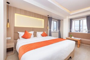 A hotel room with a large bed, a sofa, a small table, and a city view. - 14 LUXE By Mums Home (Kathmandu)