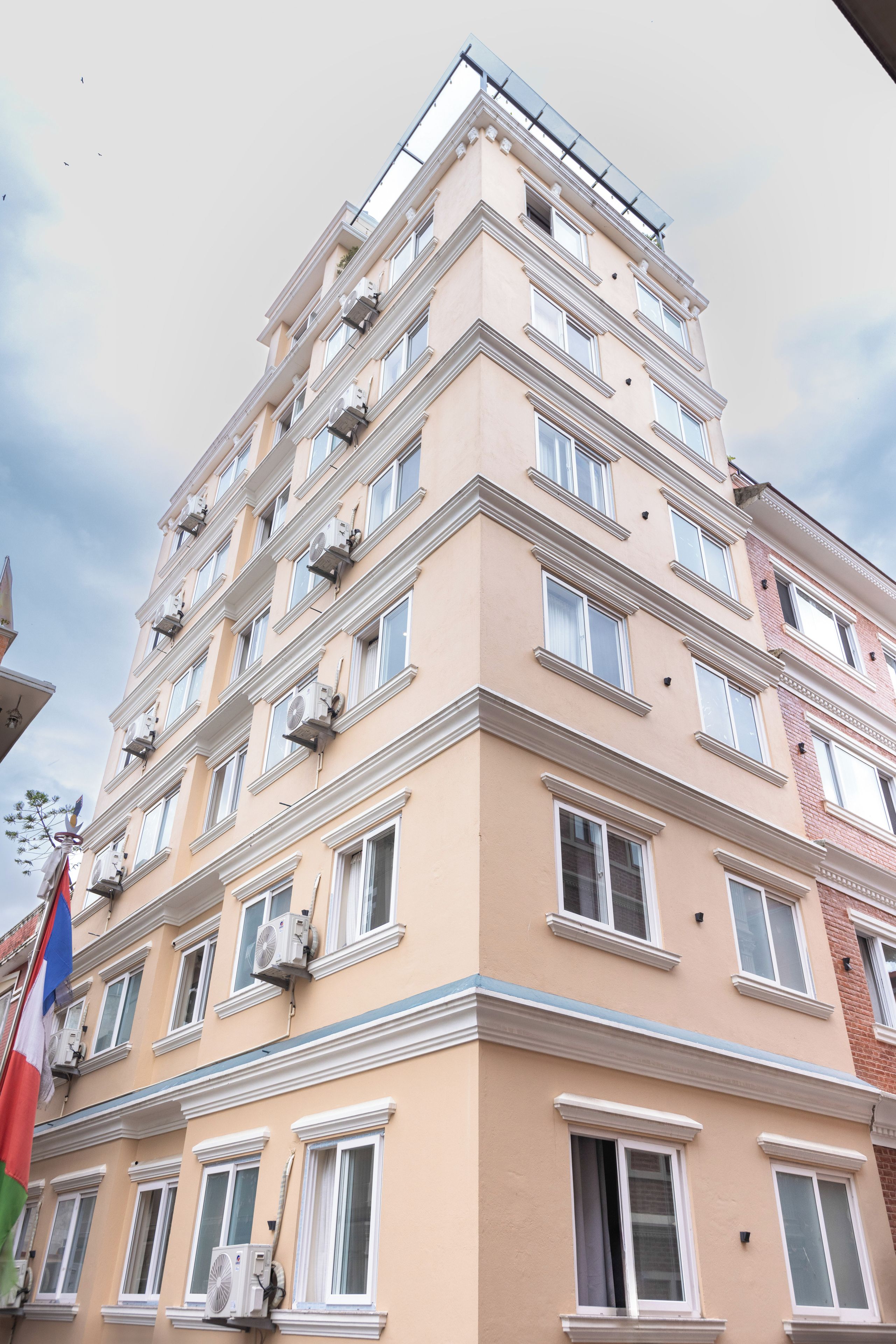 A multi-story building with a beige facade, multiple balconies, and air conditioning units.