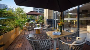 Une terrasse extérieure aménagée avec des meubles en osier, une table en bois et un grand parasol.