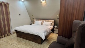 Ein Schlafzimmer mit einem Bett, einem Sessel, einem Deckenventilator und einer Wandleuchte.