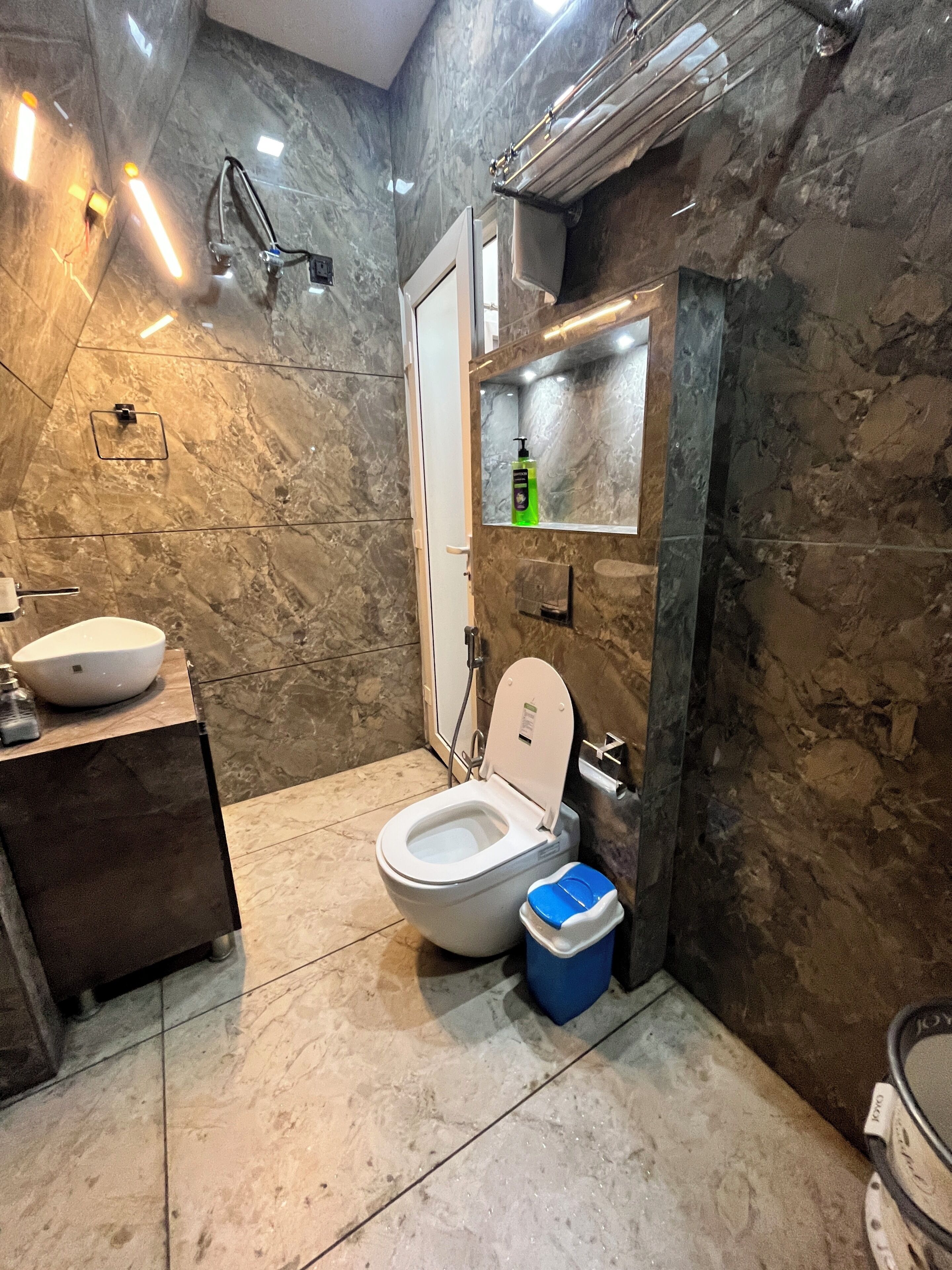 A modern bathroom with a marble floor, a white toilet, a sink with a basin, and a mirror above the sink.