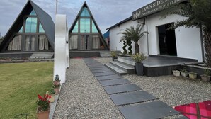 Ein modernes Gebäude mit markantem Satteldach, einem Kiesweg, der zum Eingang führt, und einem Schild mit der Aufschrift 'Lawn Side Manor'.
