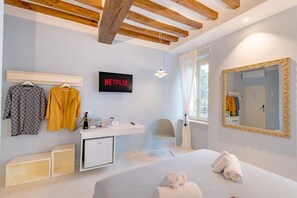 A hotel room with a bed, a desk with a computer, a TV displaying 'NETFLIX,' a mirror, and a window with curtains. - GLAM PARMA (Parma)