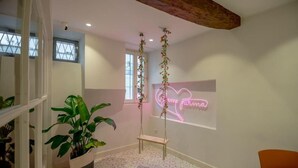 A room with a hanging plant, a neon sign, a bench, and patterned flooring. - GLAM PARMA (Parma)